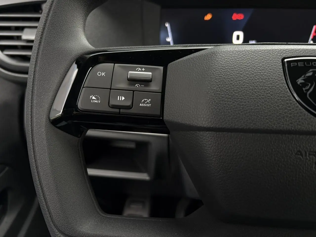 Gros plan sur les commandes à gauche du volant noir du Peugeot Expert Fourgon 2025 avec boutons de limitation et assistance.