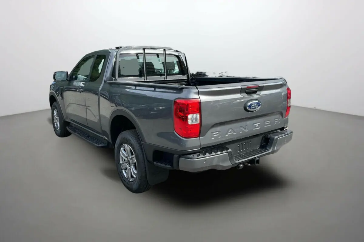 Vue 3/4 arrière du Ford Ranger gris carbone 2025 avec benne ouverte et barres de protection chromées.