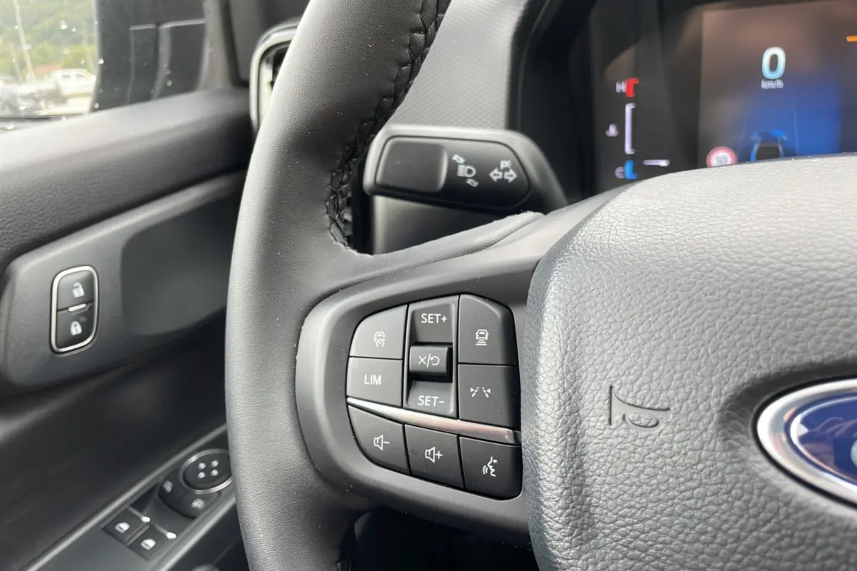 Vue rapprochée du volant cuir gris du Ford Ranger 2025 avec commandes multifonctions et tableau de bord digital.