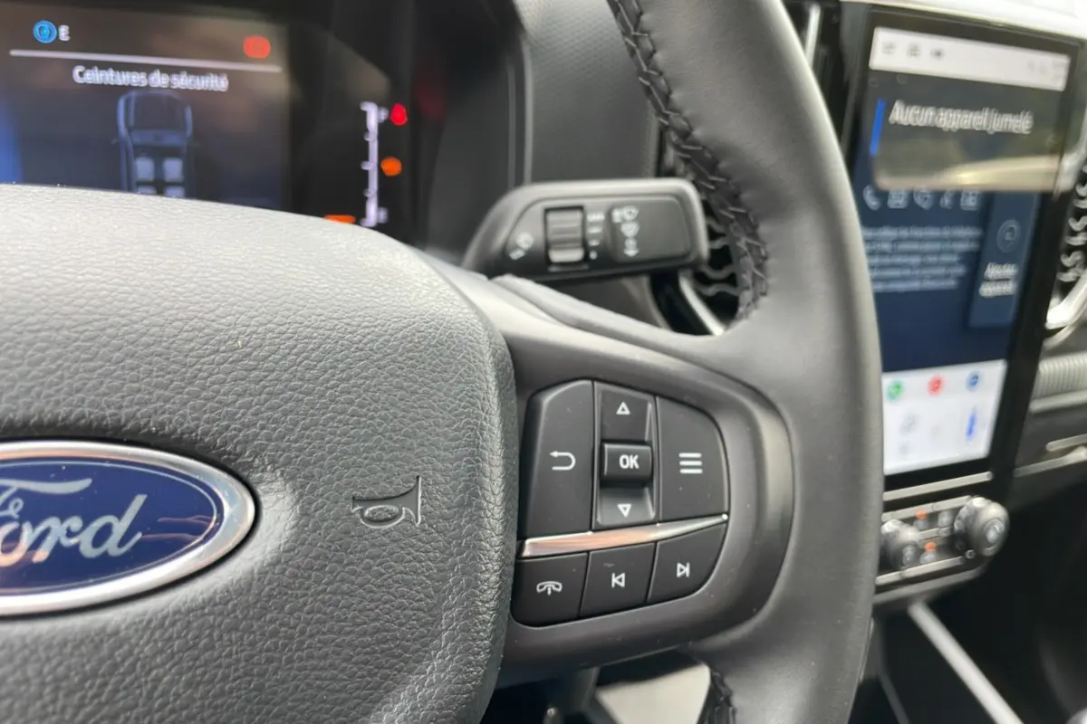 Gros plan sur le volant multifonctions en cuir du Ford Ranger 2025 avec écran tactile et commandes au volant visibles.