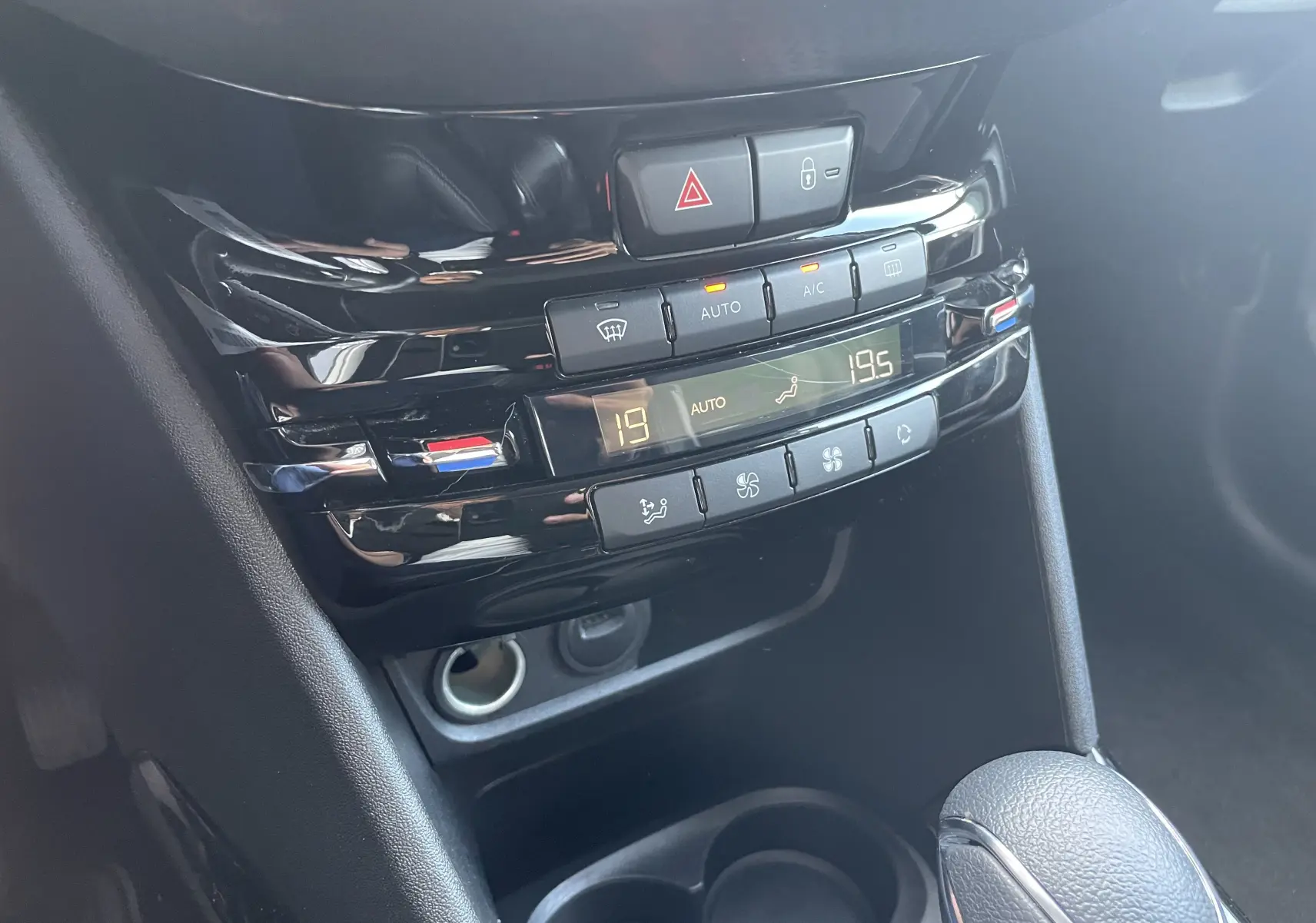Gros plan sur la console centrale noire du Peugeot 2008 2019, montrant les commandes de climatisation automatique et la boîte auto.