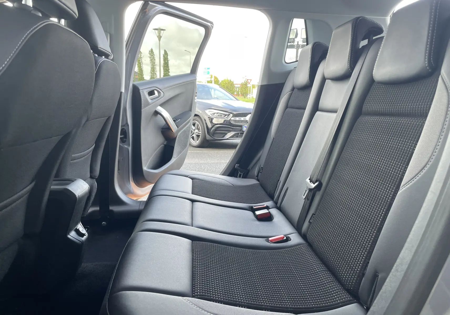 Vue intérieure sur la banquette arrière en tissu gris noir du Peugeot 2008 2019 avec porte arrière ouverte côté gauche.