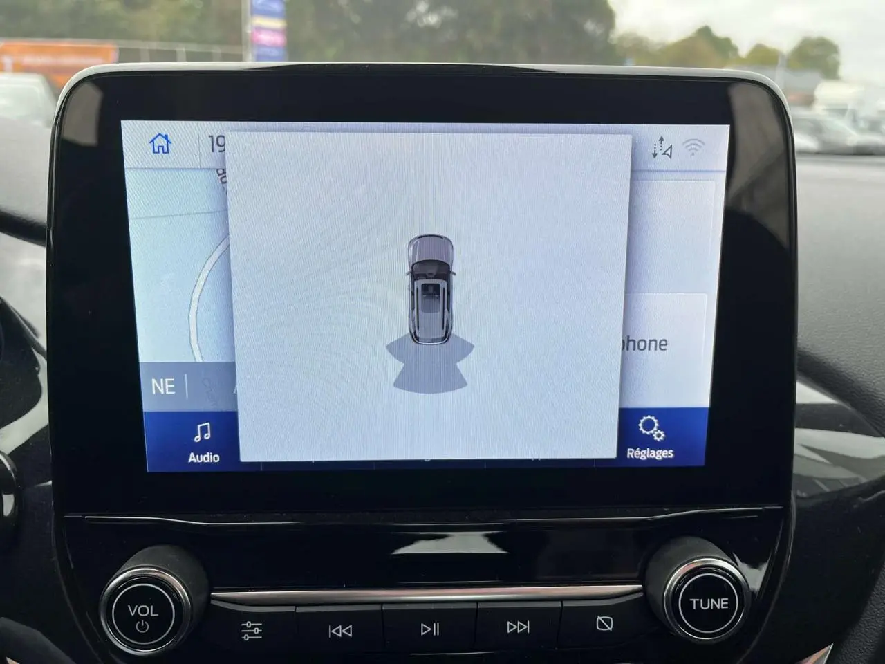 Écran tactile central du Ford Puma 2023 montrant l'assistance au stationnement avec vue du véhicule en plan dessus.