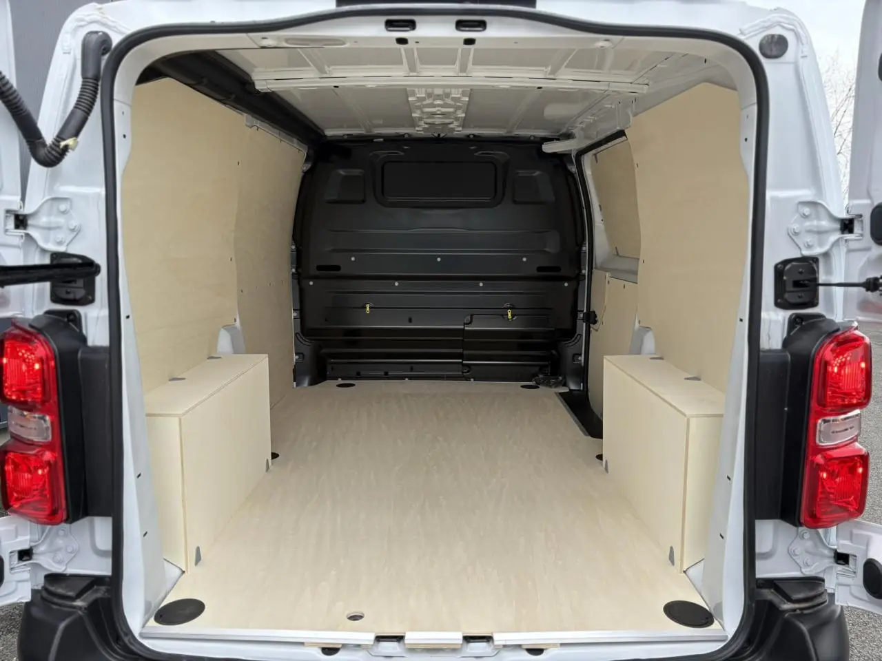 Vue arrière du Peugeot Expert Fourgon blanc Icy 2025, montrant l'espace de chargement aménagé en bois clair.