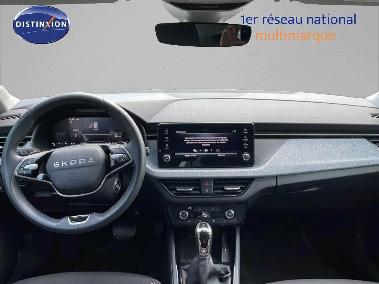 Vue intérieure frontale du Skoda Scala blanc glacier 2025, tableau de bord moderne avec écran tactile central et volant multifonction.