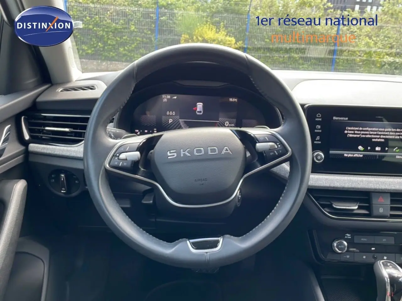 Vue intérieure centrée sur le volant noir SKODA d'une Scala 2025, avec tableau de bord digital et écran tactile.