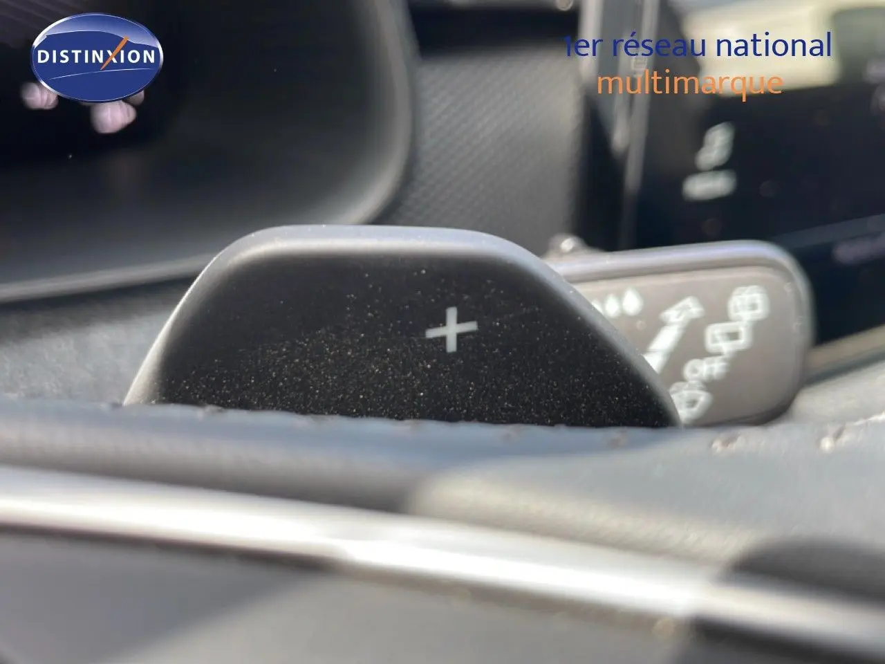 Gros plan sur la palette de changement de vitesse "+" du volant d'une Skoda Scala blanc glacier, intérieur gris noir.