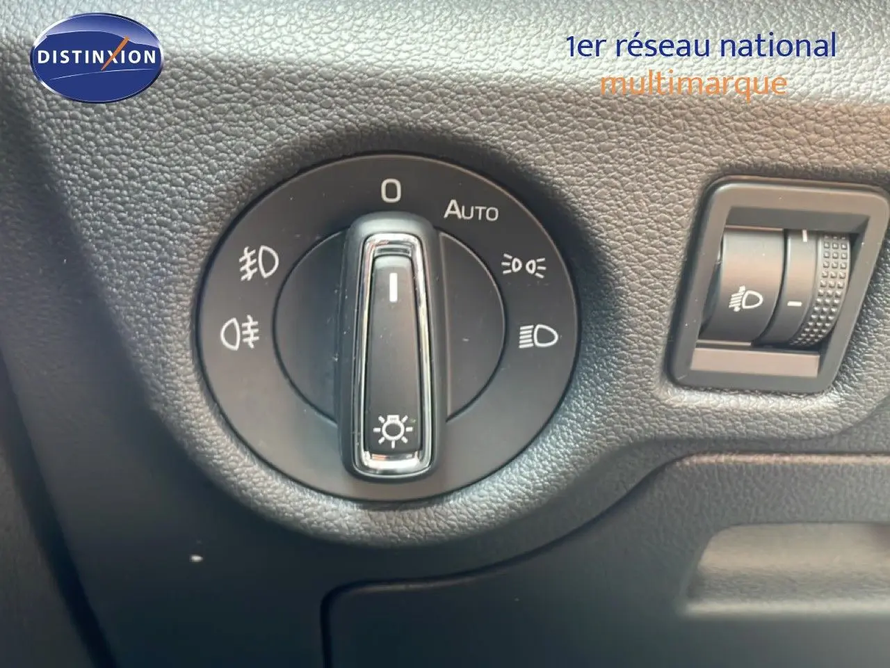 Gros plan sur la molette de réglage des phares du Skoda Scala blanc glacier, intérieur noir texturé.