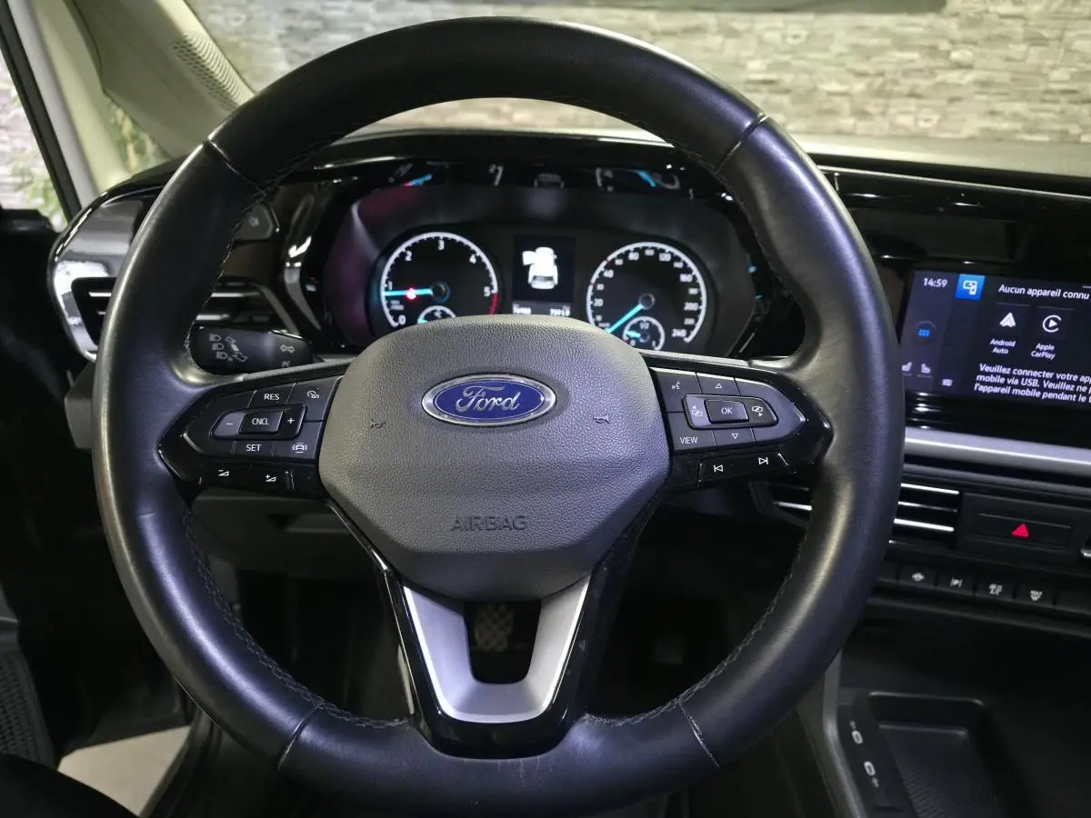 Vue rapprochée du volant noir en cuir du Ford Transit Connect 2023 avec tableau de bord et écran tactile visibles.