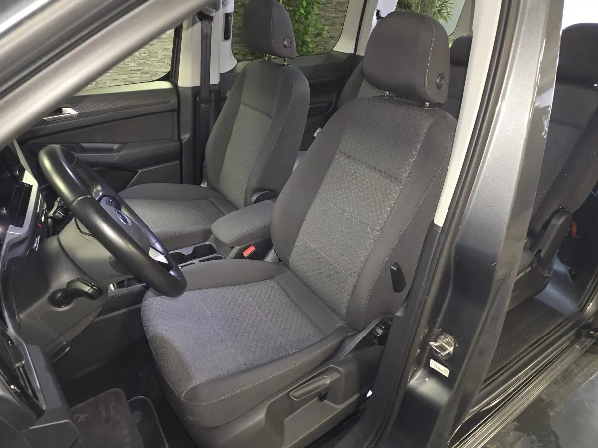 Vue intérieure côté conducteur du Ford Transit Connect gris 2023, montrant les sièges avant en tissu gris.