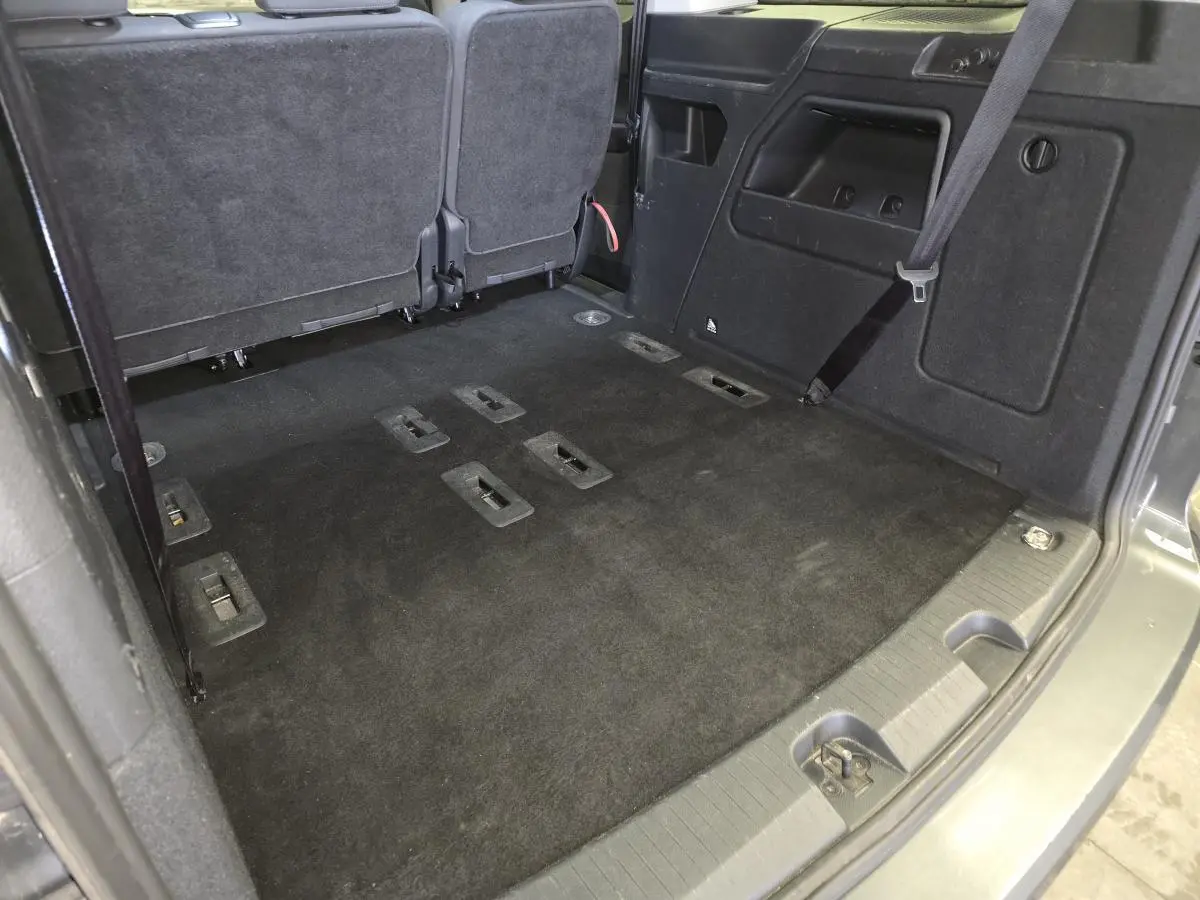 Vue intérieure arrière du coffre noir du Ford Transit Connect Tourneo Connect 2023 avec sièges rabattus et ceinture de sécurité visible.