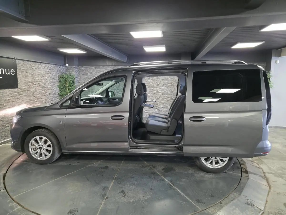 Vue de profil droit du Ford Transit Connect gris métallisé avec porte coulissante arrière ouverte montrant les sièges 7 places.