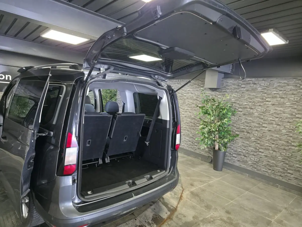 Vue arrière ouverte du Ford Transit Connect gris métallisé montrant les sièges arrière et le coffre vide.