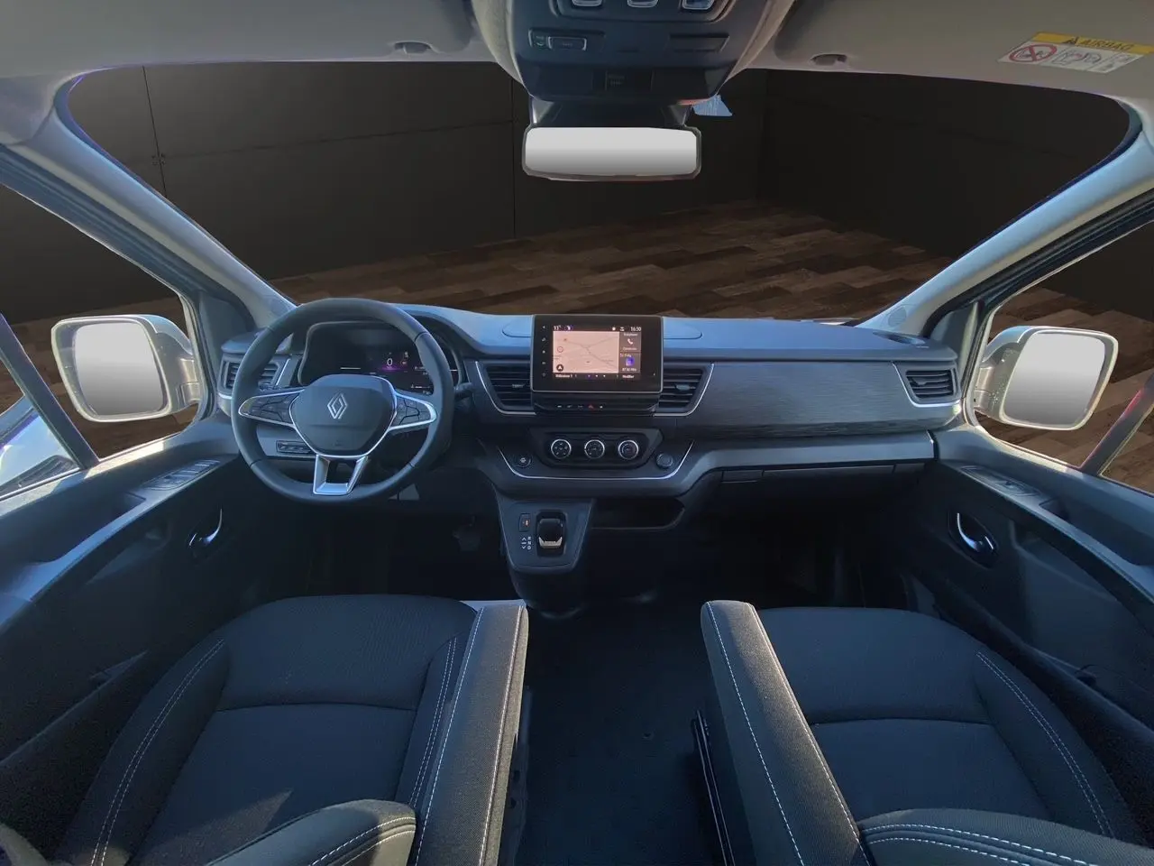 Vue intérieure avant du Renault Trafic Combi 2025 avec tableau de bord noir, volant multifonction et écran tactile central.