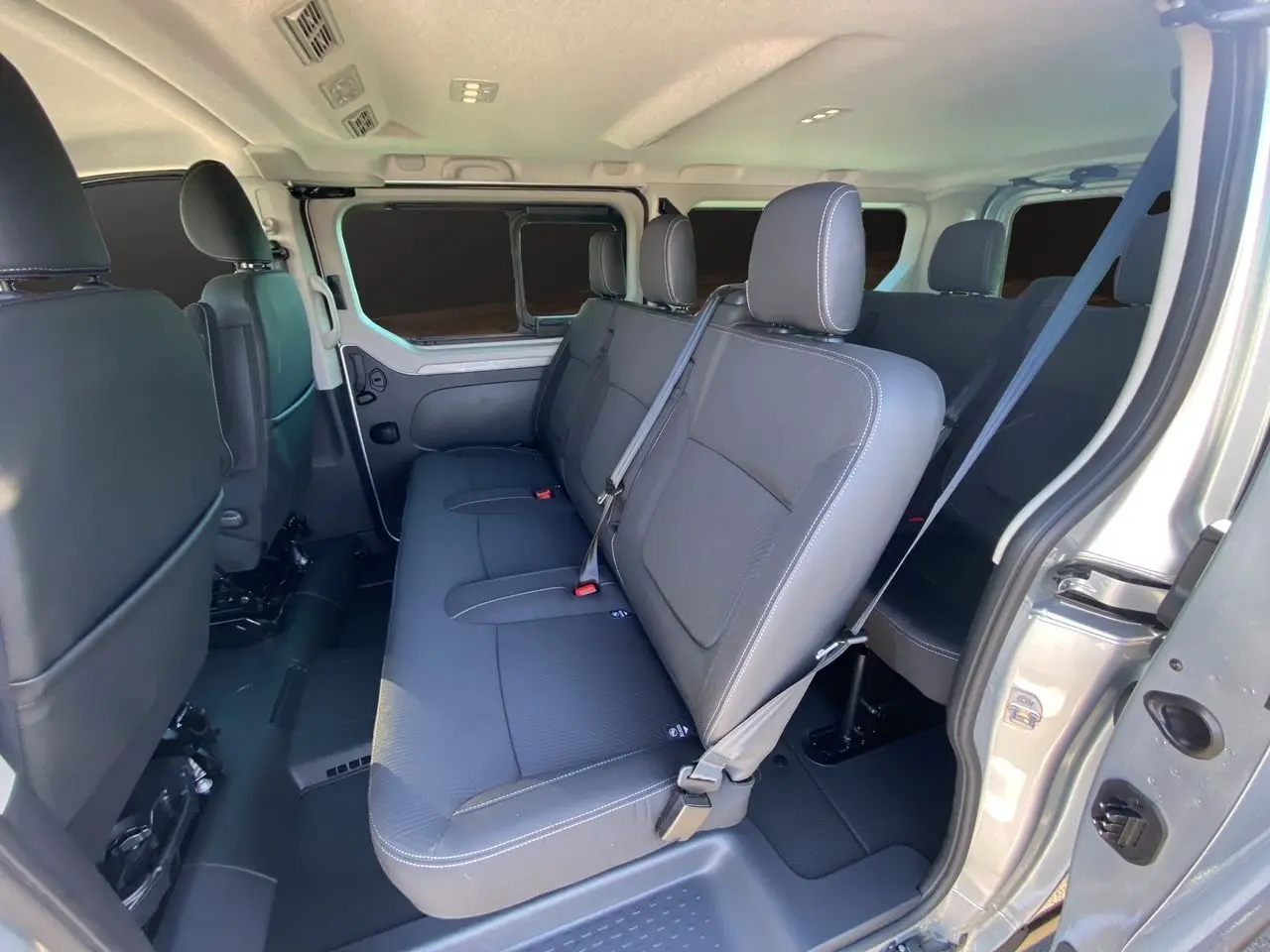 Intérieur du Renault Trafic Combi L2 Grand Techno 8 places, vue côté droit sur les sièges tissu noir et ceinture de sécurité.
