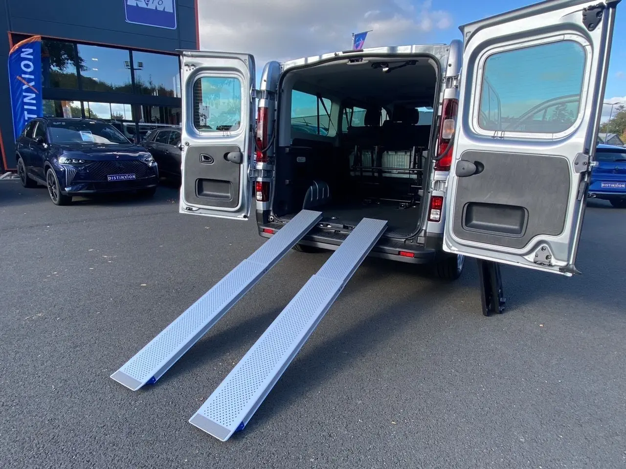 Vue arrière du Renault Trafic Combi gris Highland 2025 avec portes ouvertes et rampes d'accès déployées.