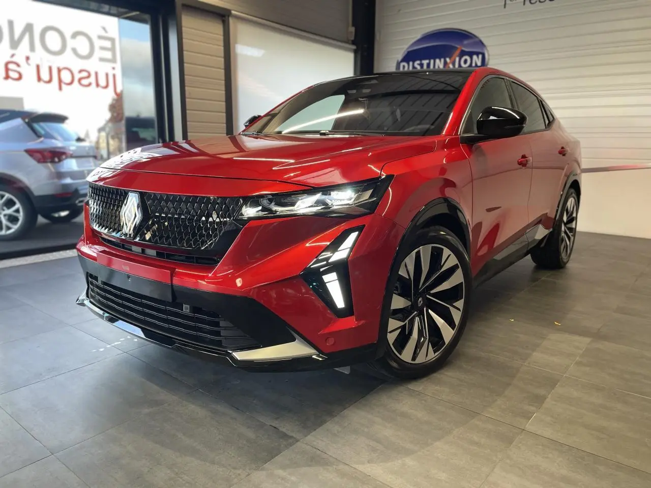 Renault Rafale rouge à toit noir en 3/4 avant droit, avec calandre 3D et feux LED distinctifs allumés.