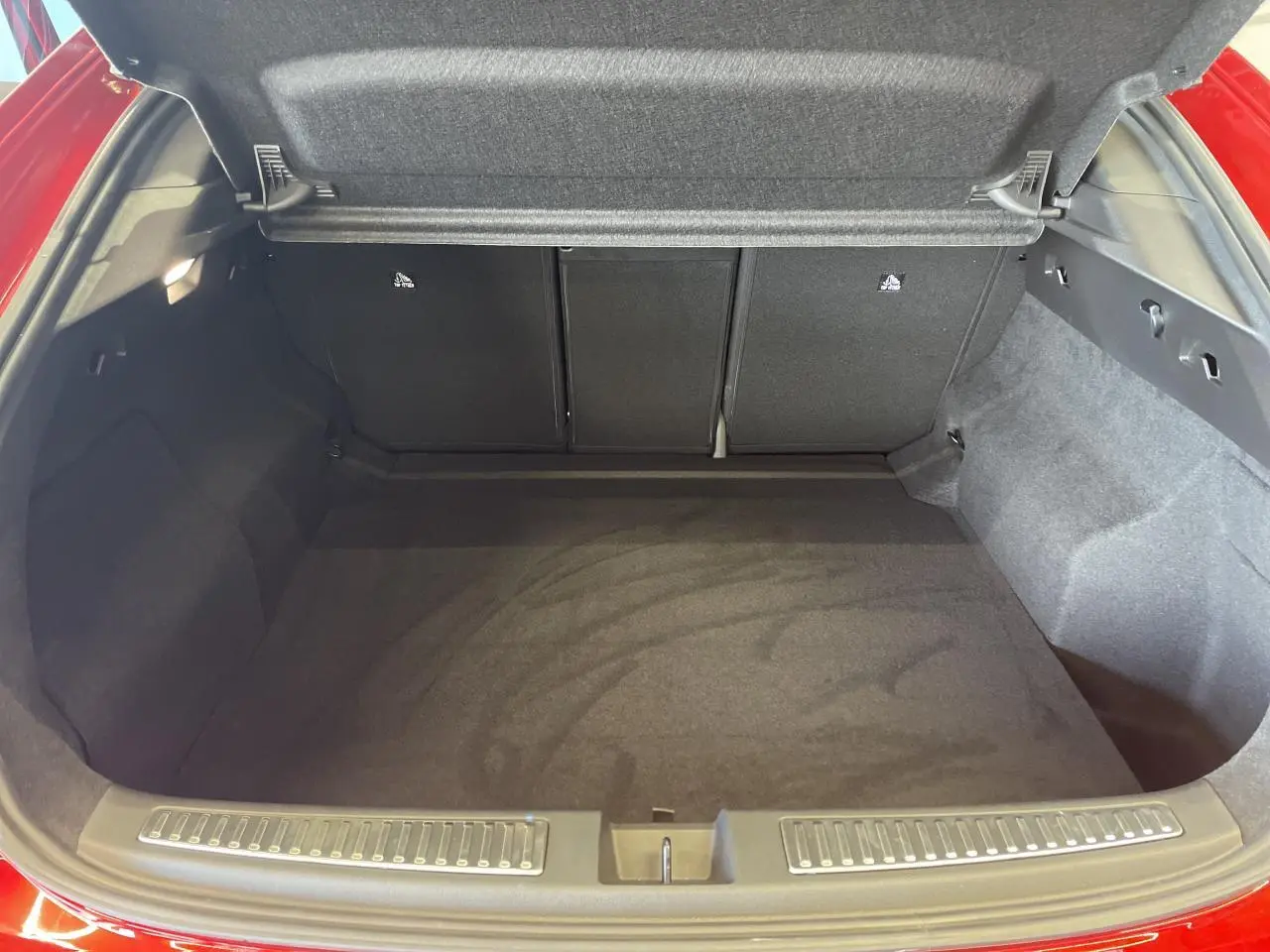 Coffre ouvert vu de l'arrière d'une Renault Rafale rouge avec toit noir, montrant l'espace de chargement vide.