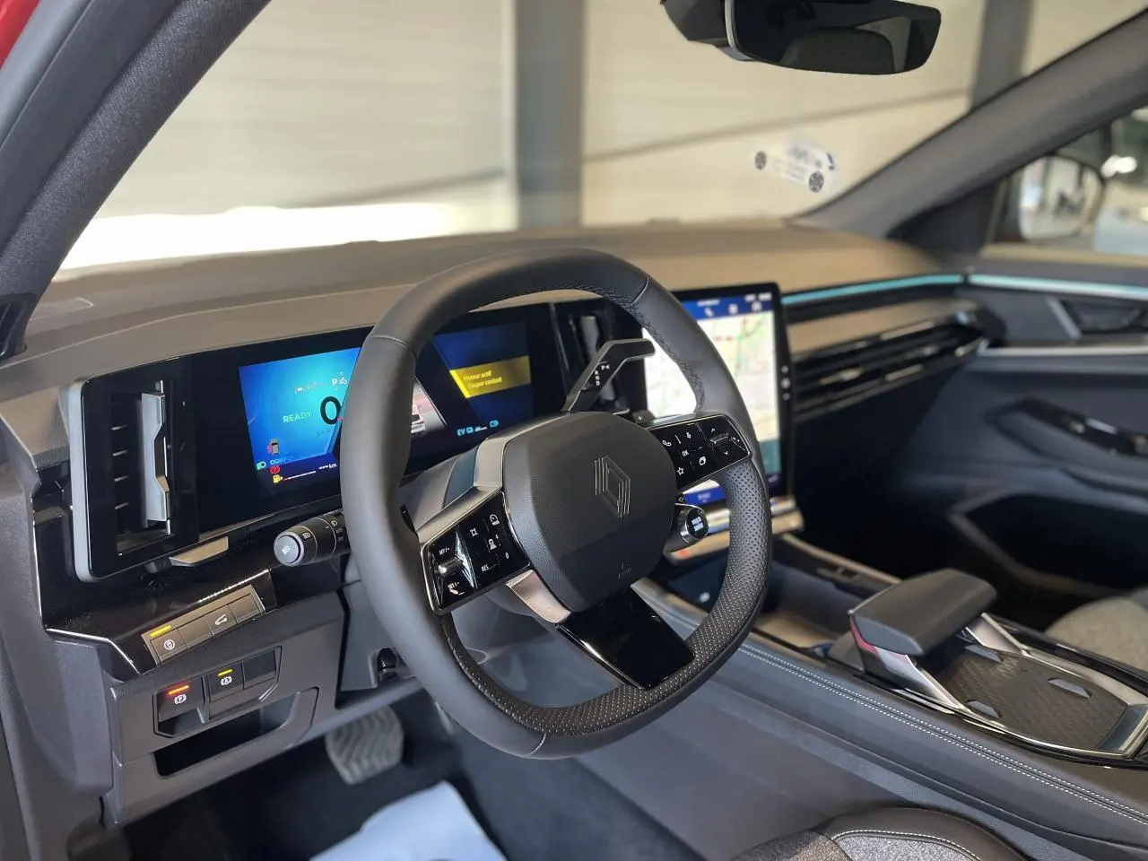 Intérieur de la Renault Rafale 2025, vue du poste de conduite avec volant multifonction et écran tactile central lumineux.