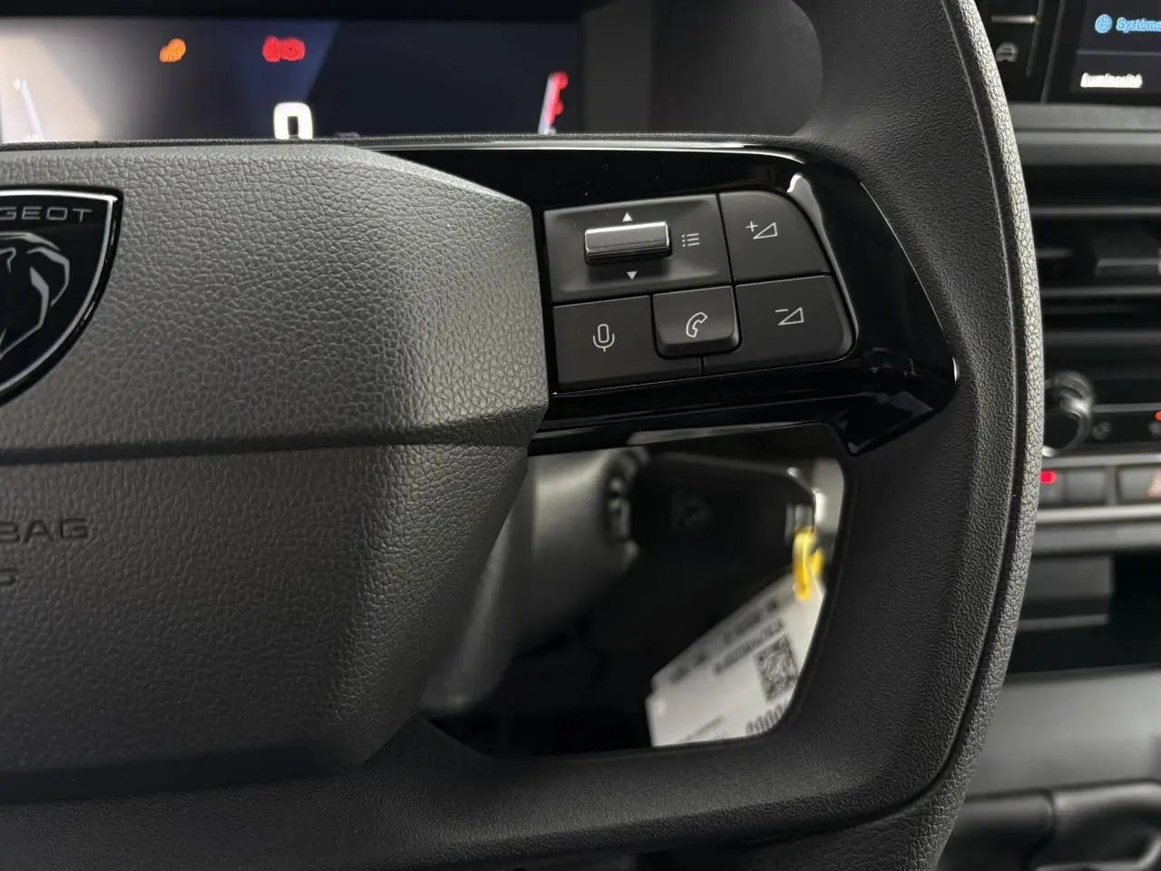 Gros plan sur les commandes vocales et téléphone du volant noir du Peugeot Expert Fourgon 2025, intérieur moderne.