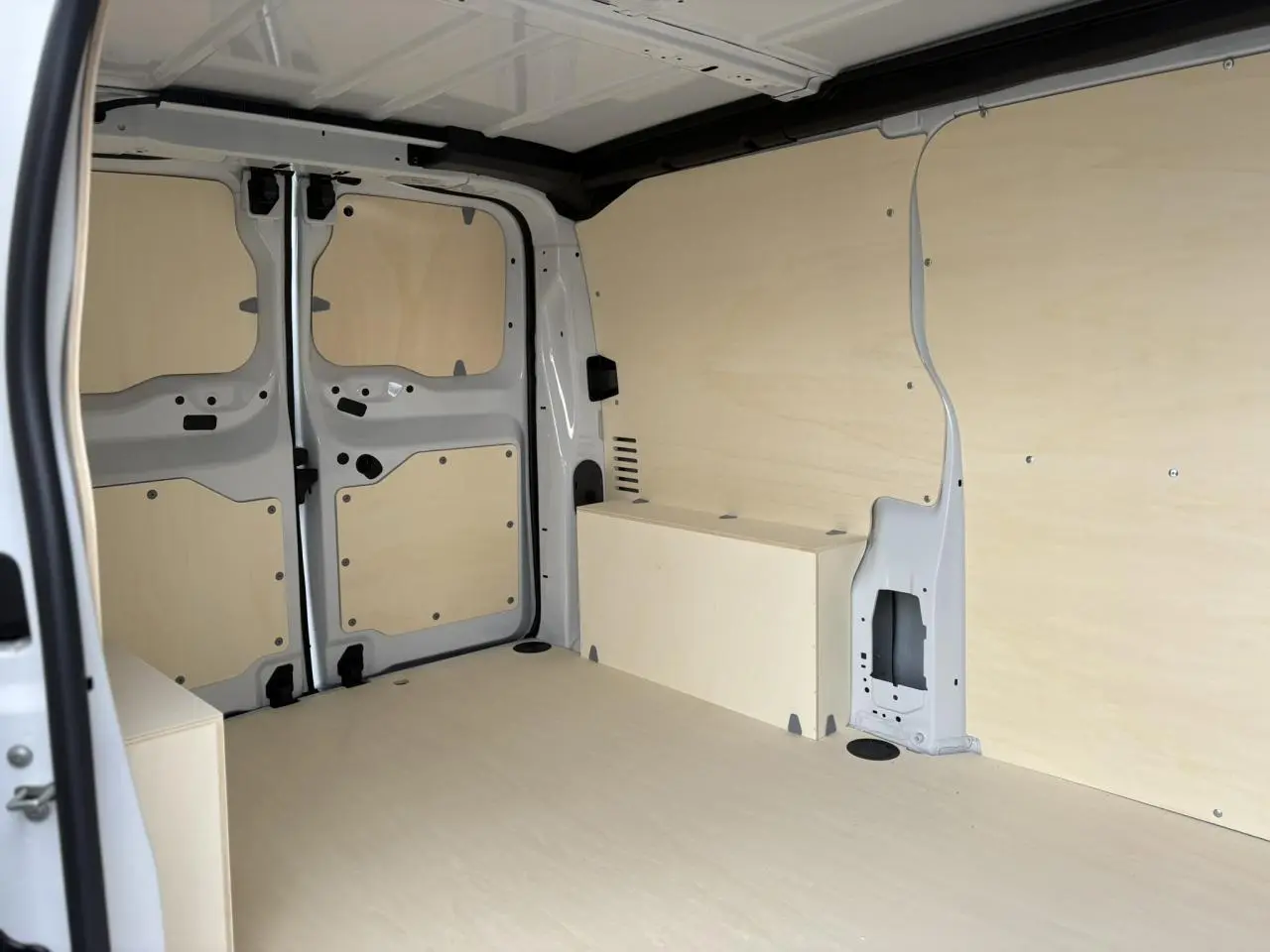 Intérieur arrière du Peugeot Expert Fourgon blanc Icy, vue côté gauche avec parois et sol en bois clair.