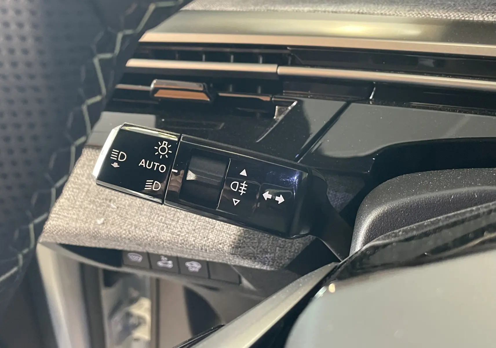 Gros plan sur la commande des feux et clignotants du Peugeot 3008 Hybrid 145, finition GT Exclusive, intérieur tissu gris.