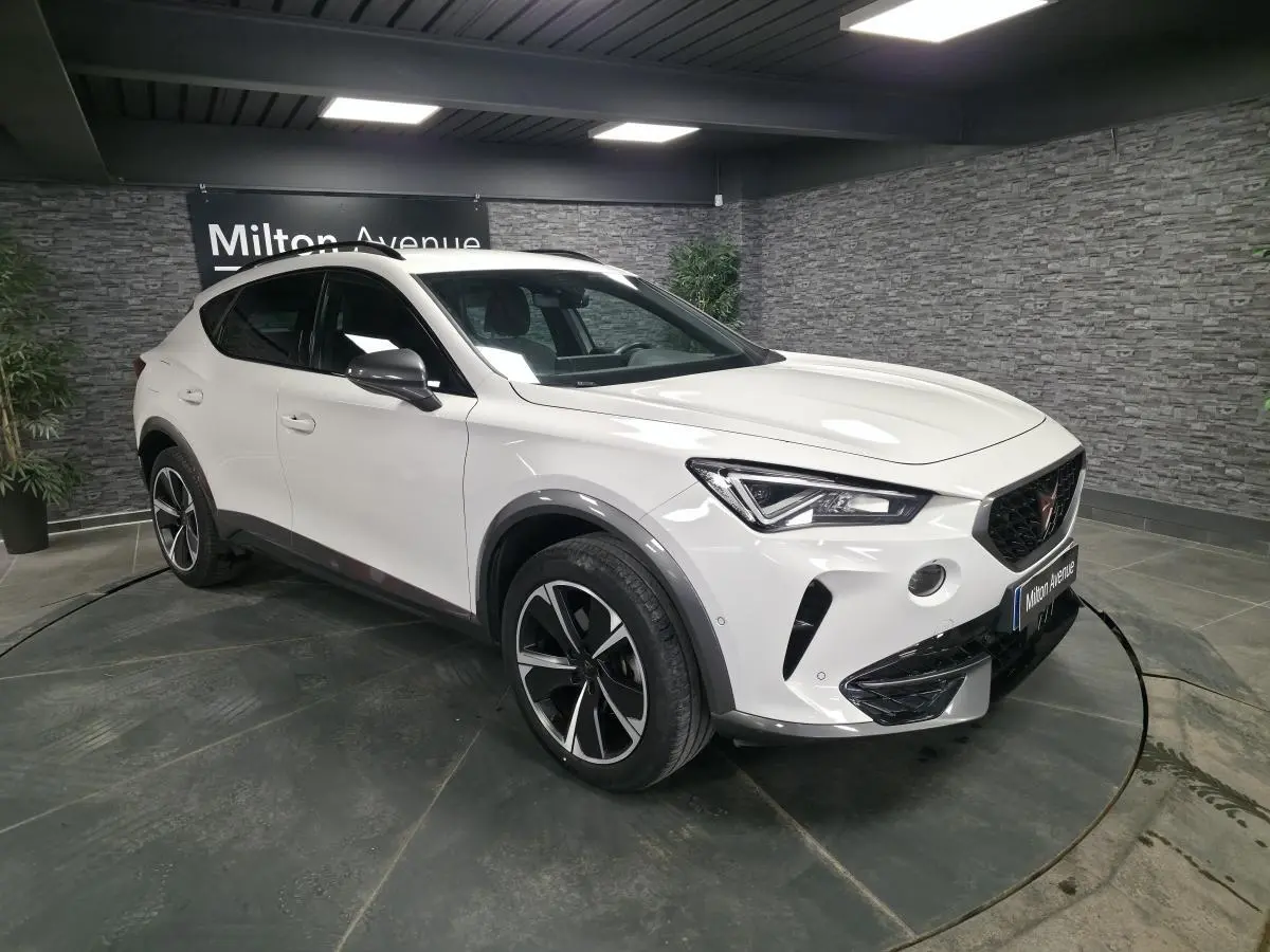 Vue 3/4 avant d'un CUPRA Formentor blanc avec jantes alliage noires et détails contrastants Dark Alu dans un showroom.