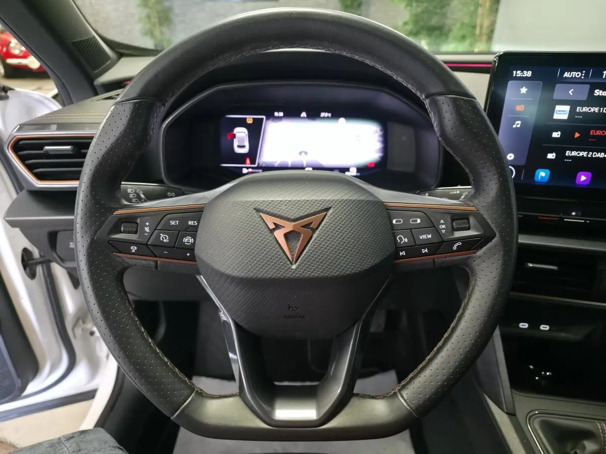 Vue rapprochée du volant sport en cuir noir avec logo CUPRA cuivré, tableau de bord digital et écran tactile du Formentor blanc 2024.