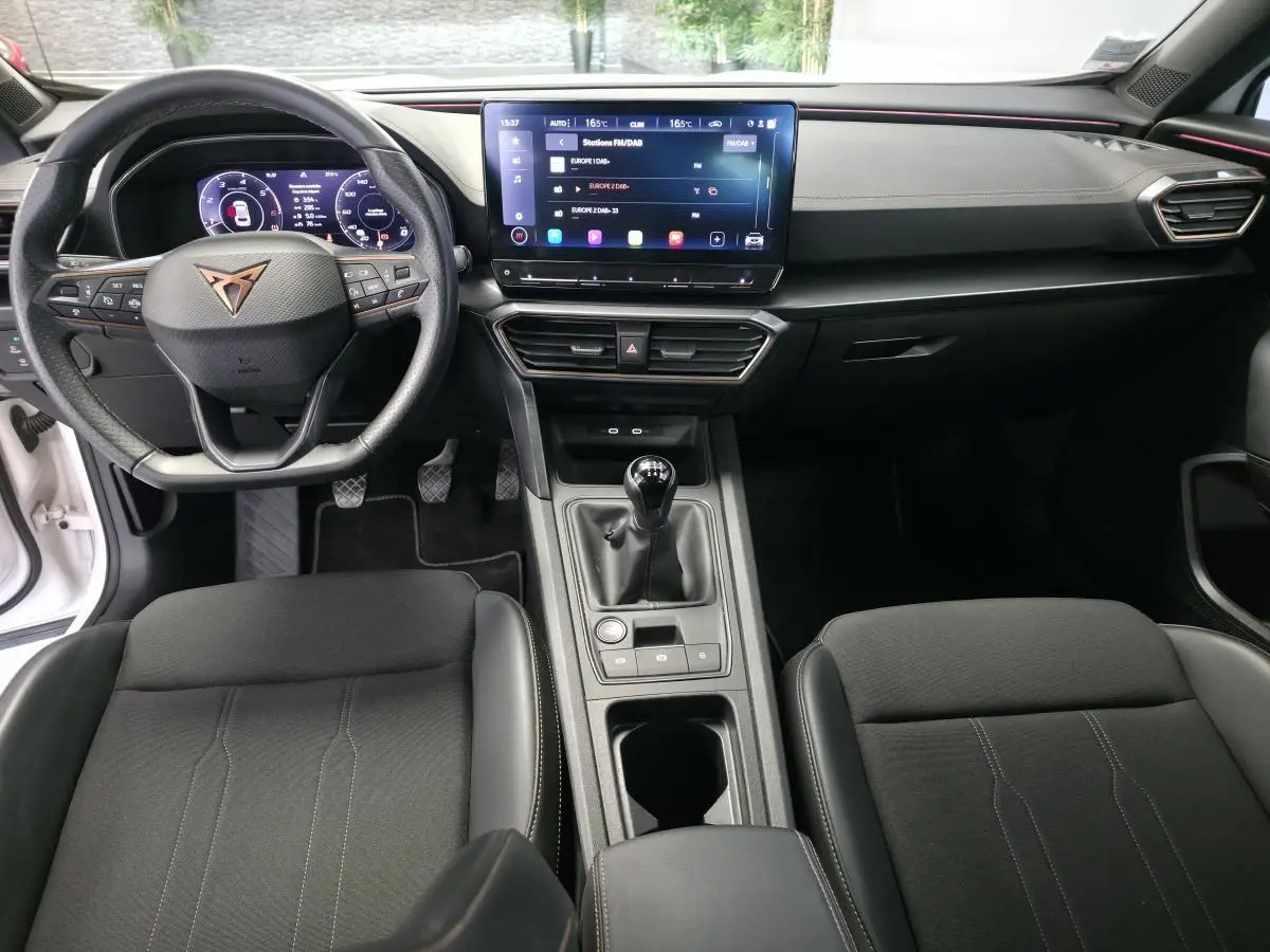 Intérieur avant du CUPRA Formentor blanc 2024, vue du tableau de bord avec volant cuir, écran tactile et boîte manuelle.