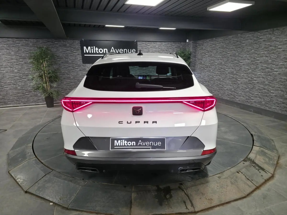 Vue arrière d'un CUPRA Formentor blanc avec bandeau lumineux LED rouge et double sortie d'échappement noire.