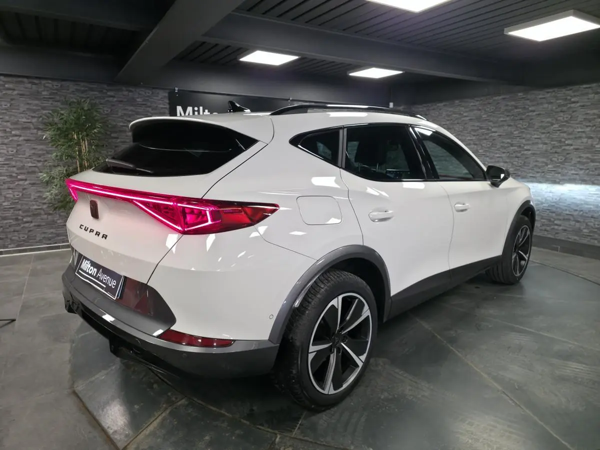 Vue 3/4 arrière droite du CUPRA Formentor blanc avec bandeau LED arrière Infinite Light et jantes alliage 18 pouces.