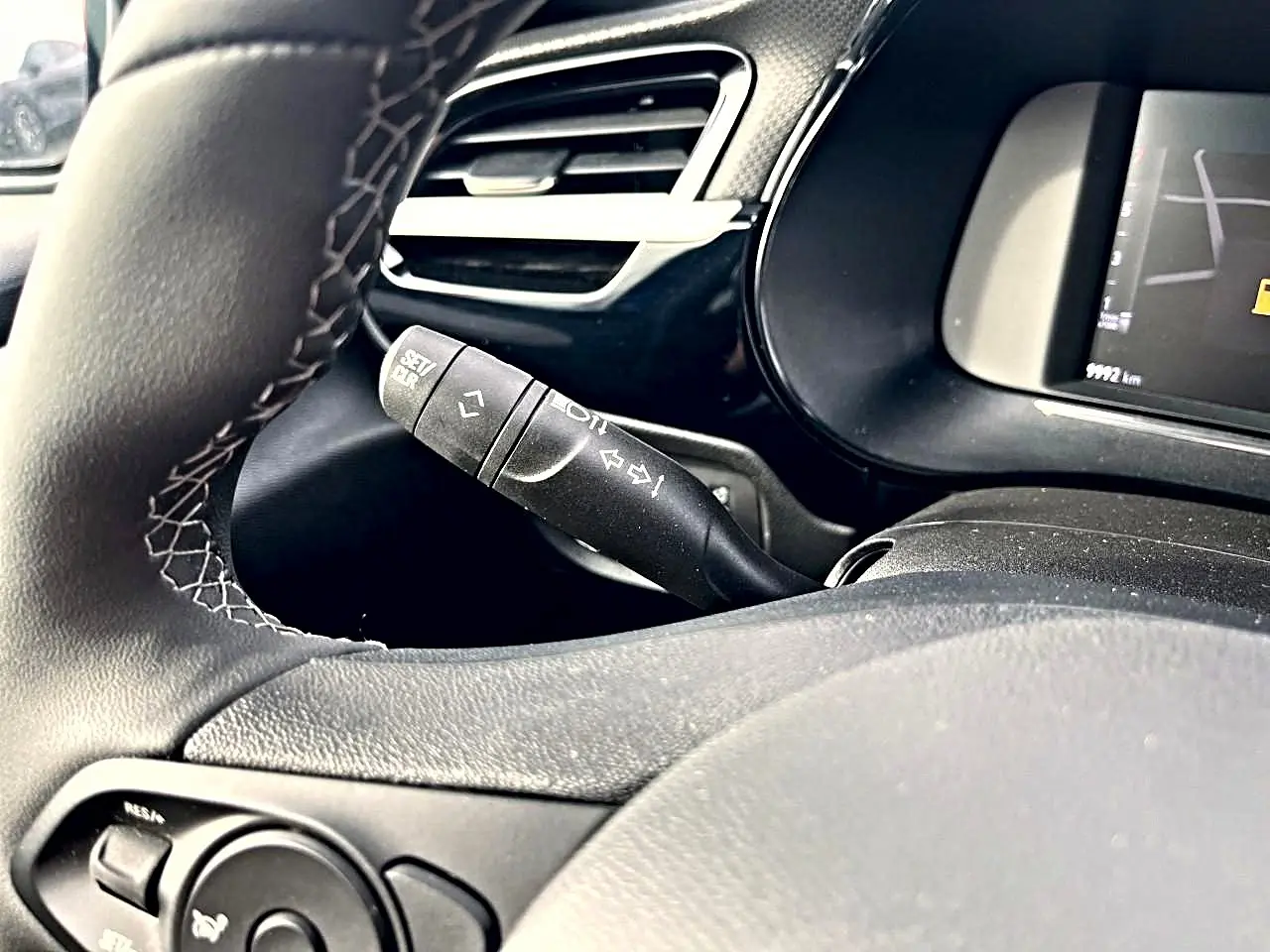 Gros plan sur la manette de clignotant et le volant noir avec surpiqûres blanches de l'Opel Corsa 1.2 turbo 2025.