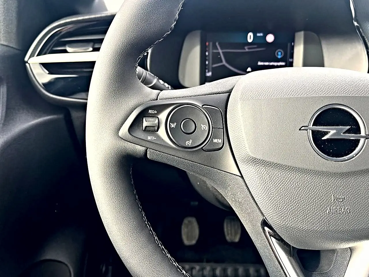 Gros plan sur le volant multifonction noir de l'Opel Corsa 2025 avec tableau de bord numérique en arrière-plan.