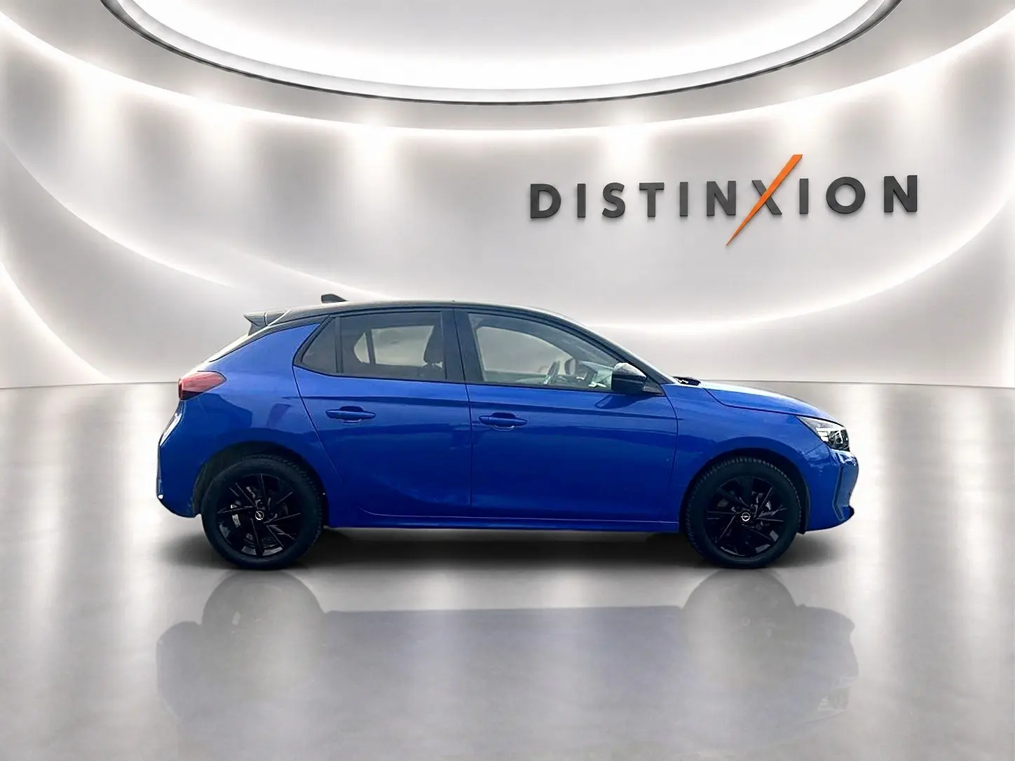 Profil droit d’une Opel Corsa bleu 2025 avec jantes noires, dans un studio lumineux marqué Distinxion.
