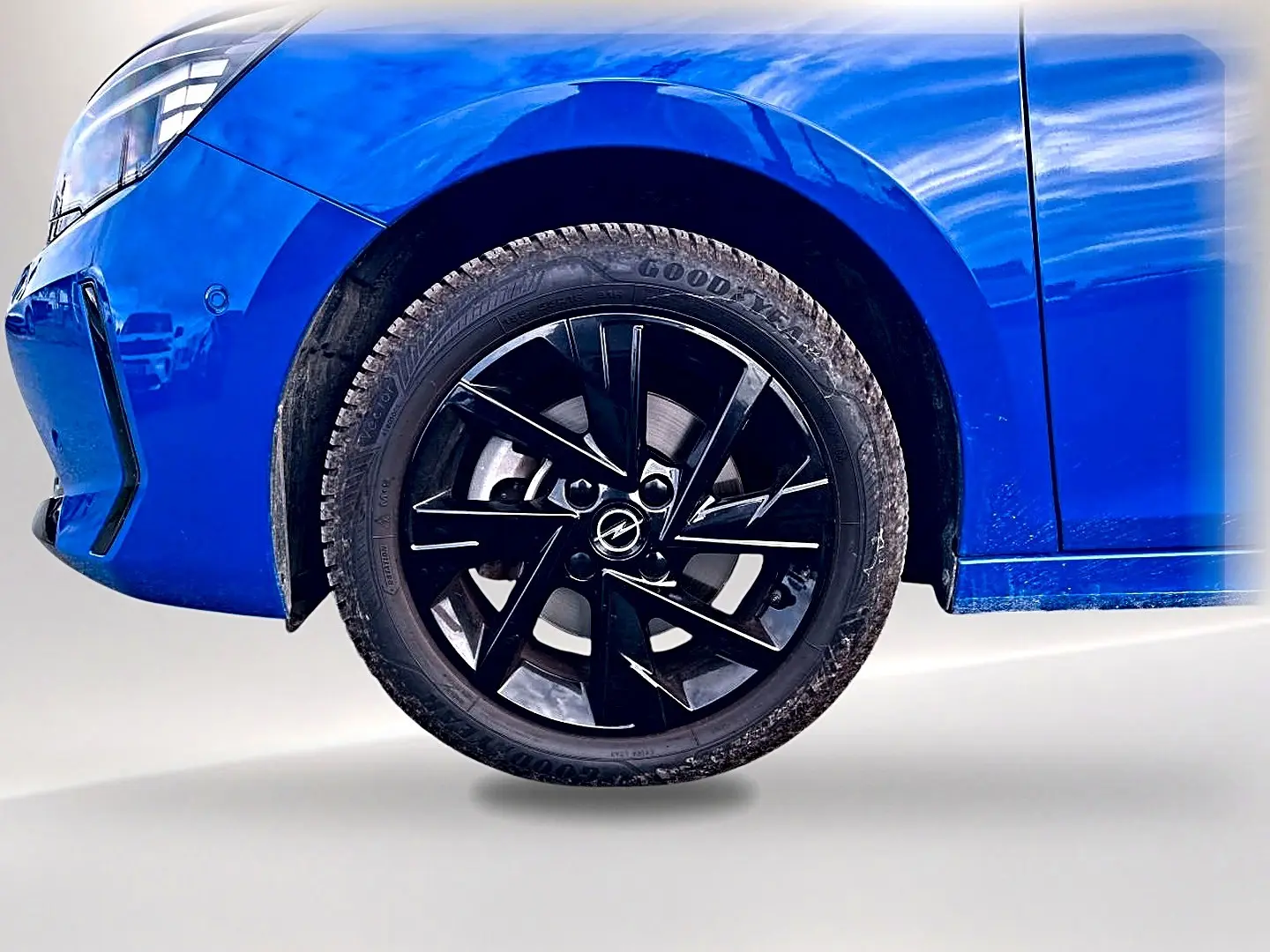 Gros plan sur la roue avant droite noire et jante alu d’une Opel Corsa bleu 2025, avec partie avant visible.