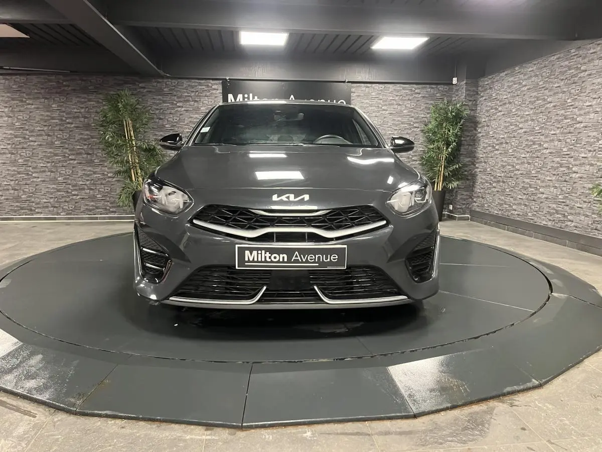Vue frontale d'une KIA Ceed 2023 gris métallisé avec calandre noire et détails chromés en showroom.