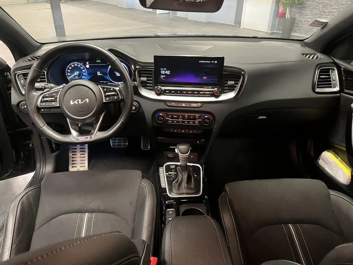 Vue intérieure avant de la Kia Ceed 2023 gris, tableau de bord moderne avec écran tactile et volant cuir multifonction.
