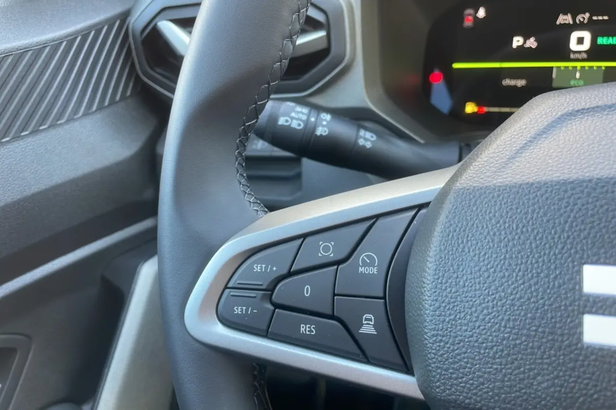 Gros plan sur le volant cuir noir du Dacia Bigster 2025, montrant les commandes de régulateur et tableau de bord digital.