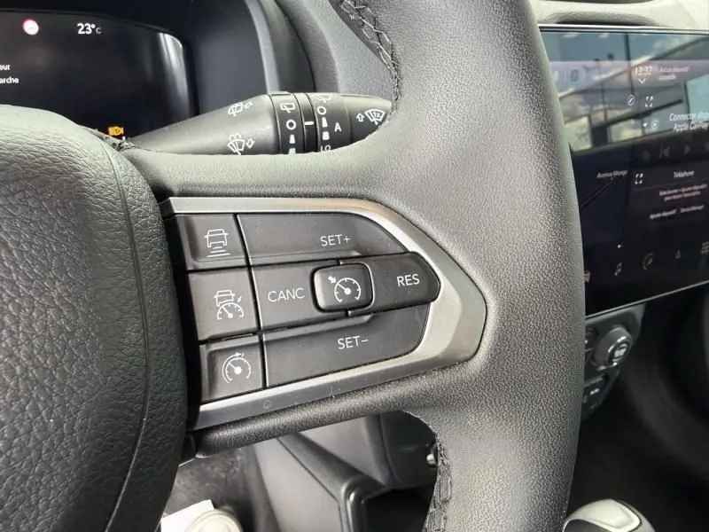Gros plan sur les commandes de régulateur de vitesse au volant d’un Jeep Renegade 2024, intérieur noir.