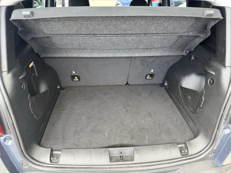 Coffre ouvert vu de l’arrière d’un Jeep Renegade 2024 bleu métal, montrant l’espace de chargement vide.