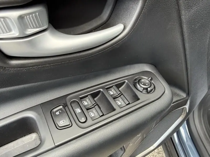 Gros plan sur les commandes de vitres et rétroviseurs côté conducteur du Jeep Renegade bleu métal 2024.
