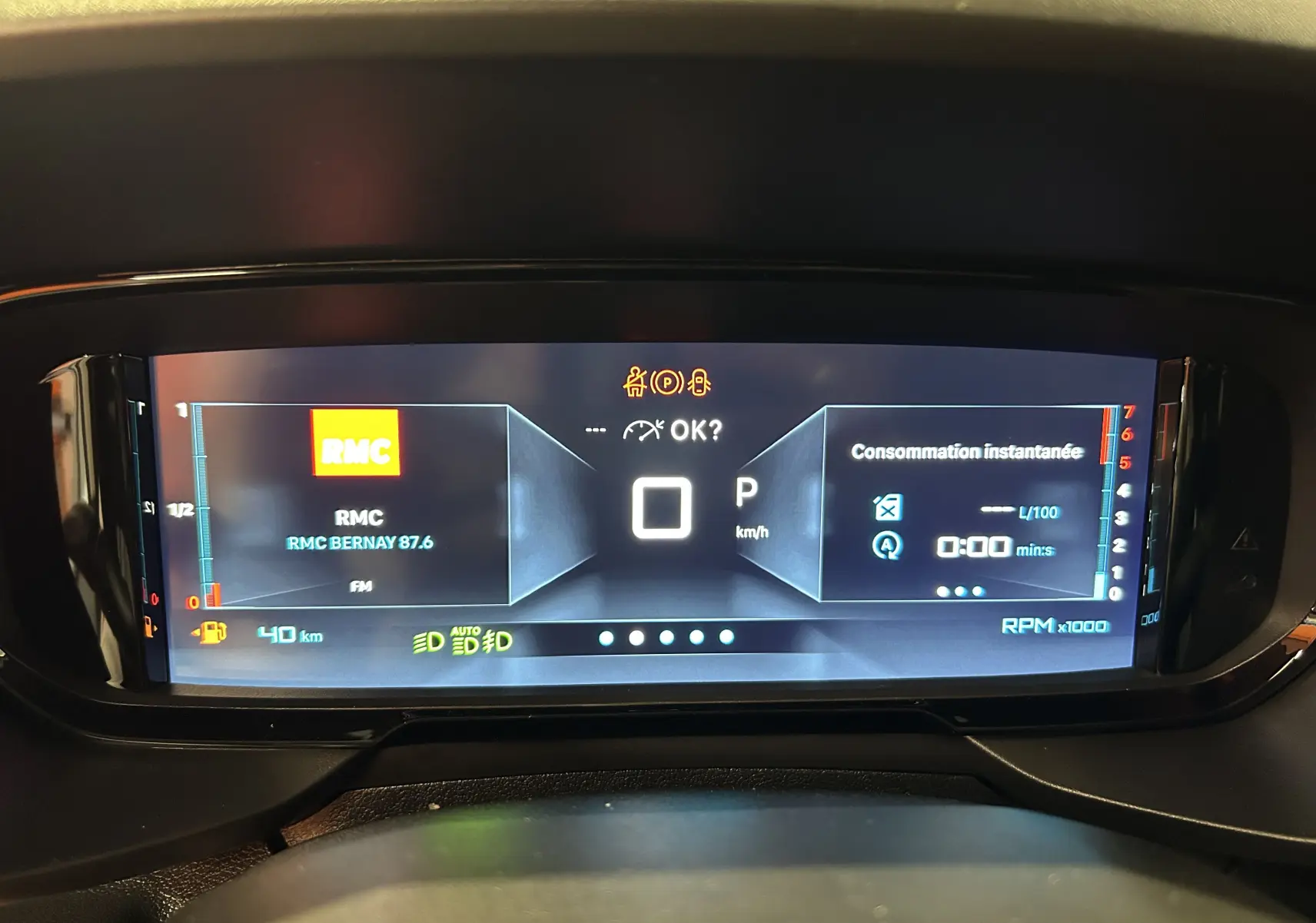 Tableau de bord numérique du Citroën Berlingo Multispace 2026 affichant la radio RMC et la consommation instantanée.