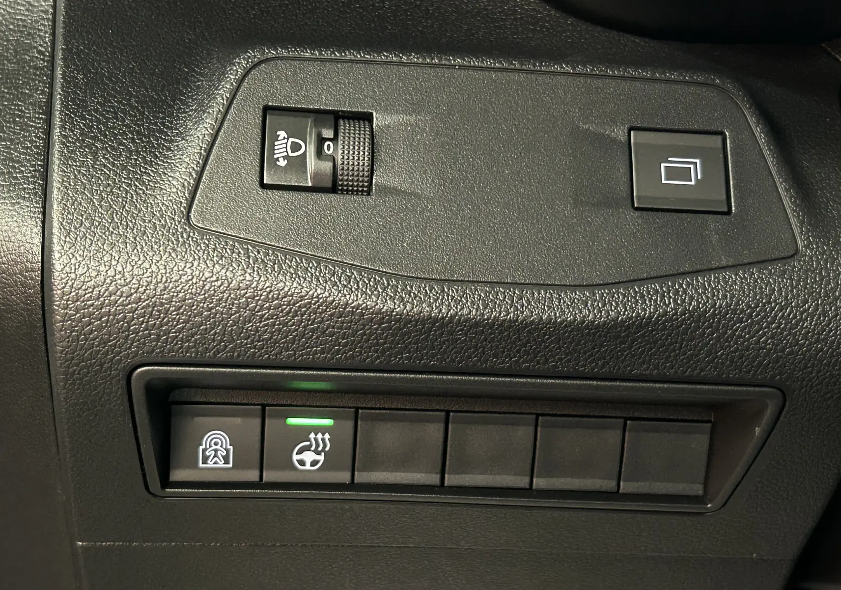 Gros plan sur les commandes noires du tableau de bord du Citroën Berlingo Multispace, avec bouton de chauffage de volant allumé.