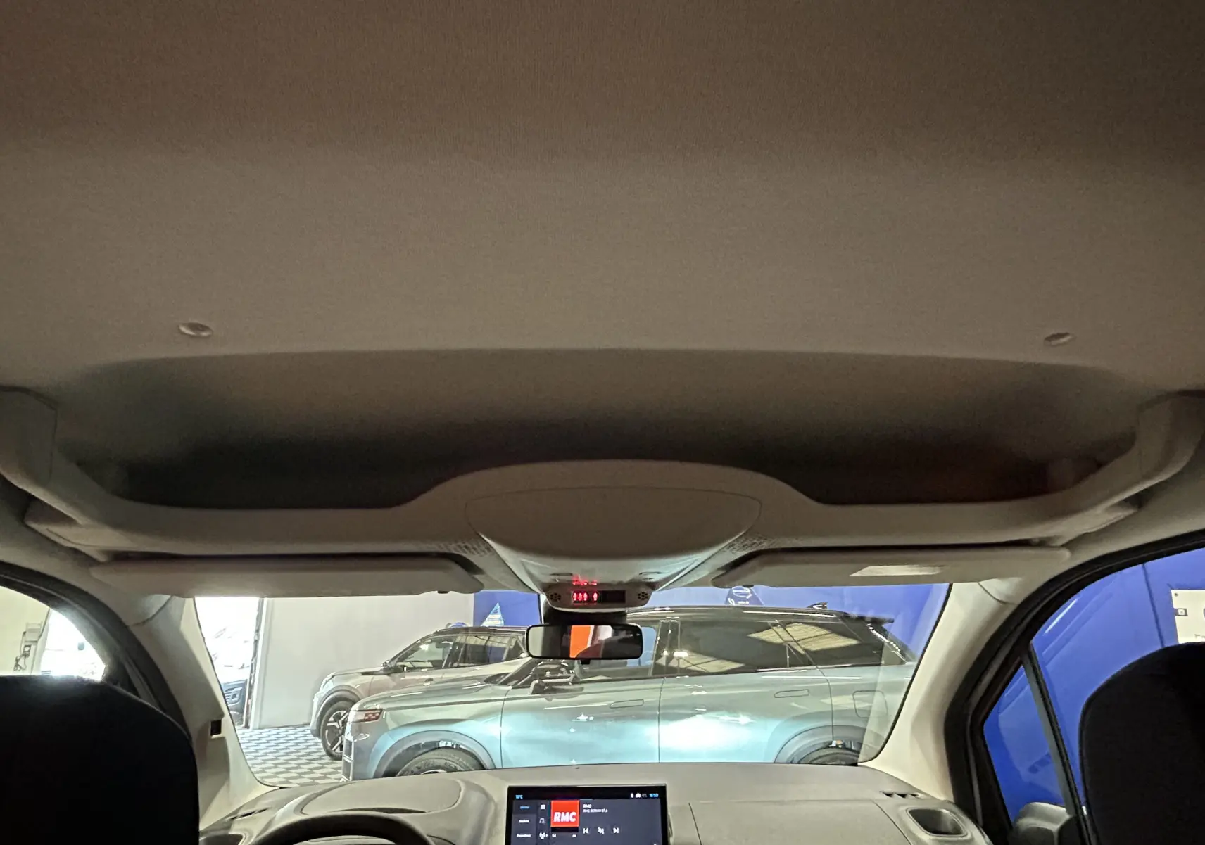 Vue intérieure du Citroën Berlingo Multispace 2026, avec tableau de bord et pare-brise montrant un SUV gris acier à l'extérieur.