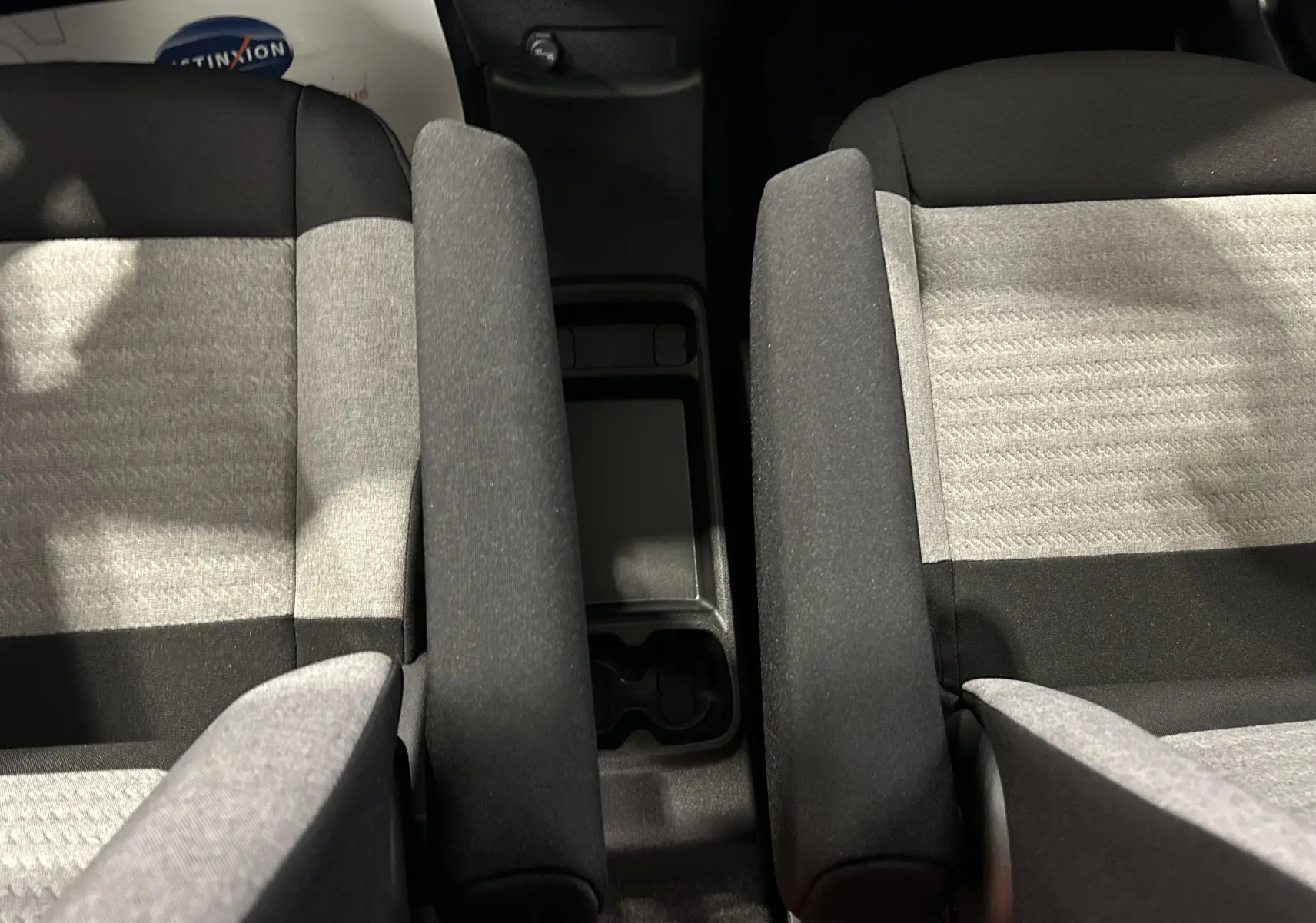 Vue plongeante sur les sièges avant gris clair et noir du Citroën Berlingo Multispace avec accoudoirs centraux relevés.