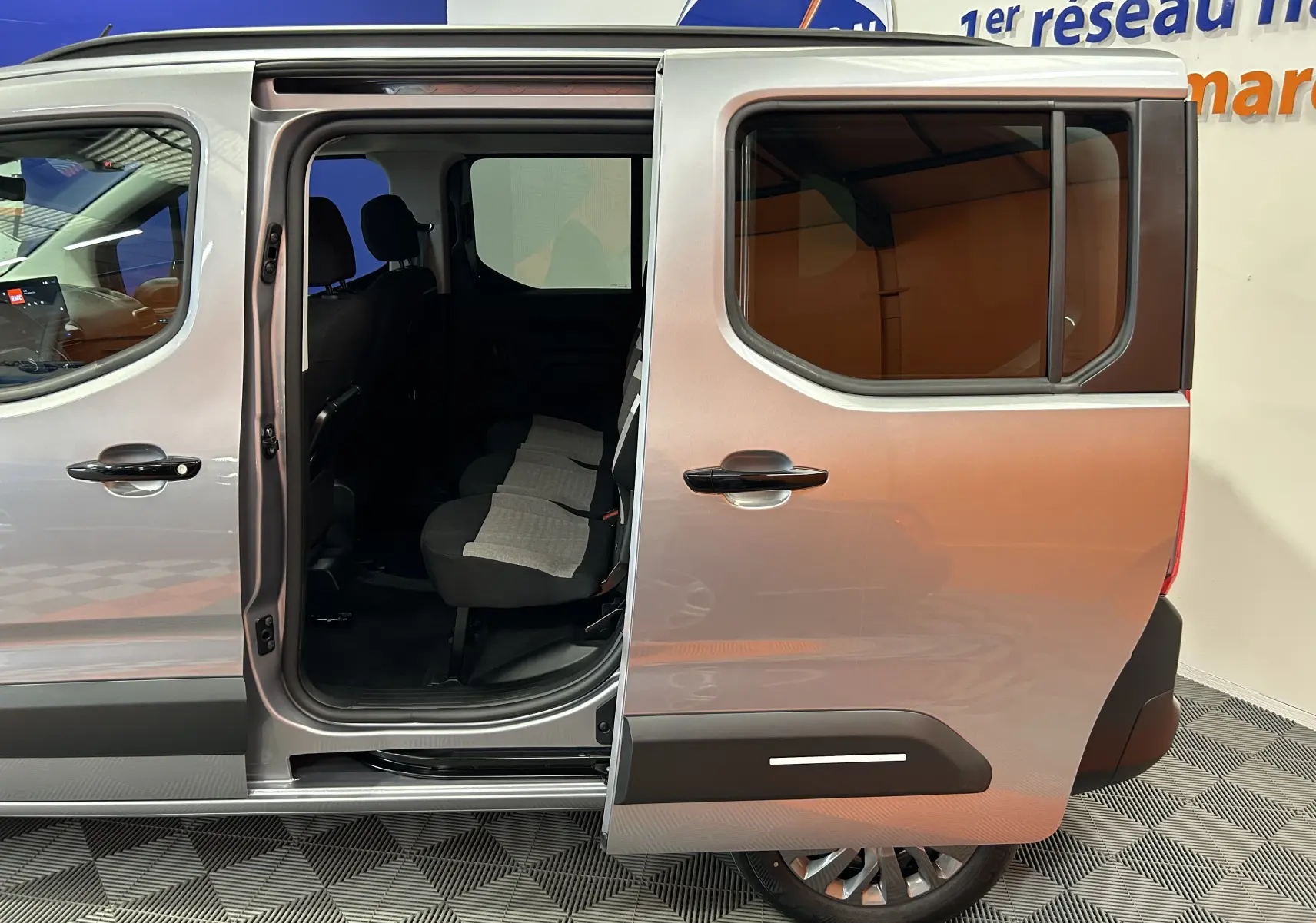 Vue latérale droite du Citroën Berlingo Multispace gris acier avec porte coulissante ouverte dévoilant les sièges arrière.