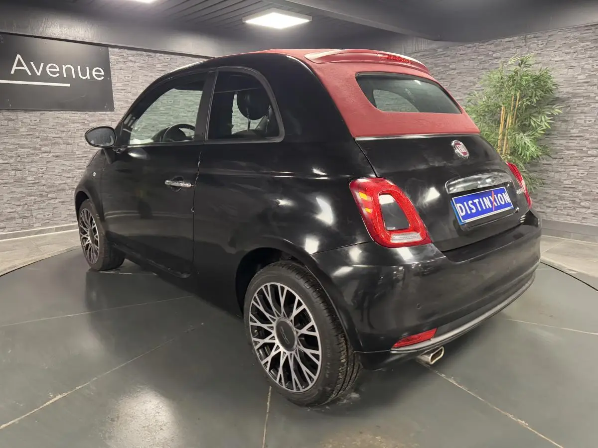 Fiat 500 Cabriolet 2024 vue 3/4 arrière côté droit, noire métallisée avec capote rouge et jantes alliage 16 pouces.