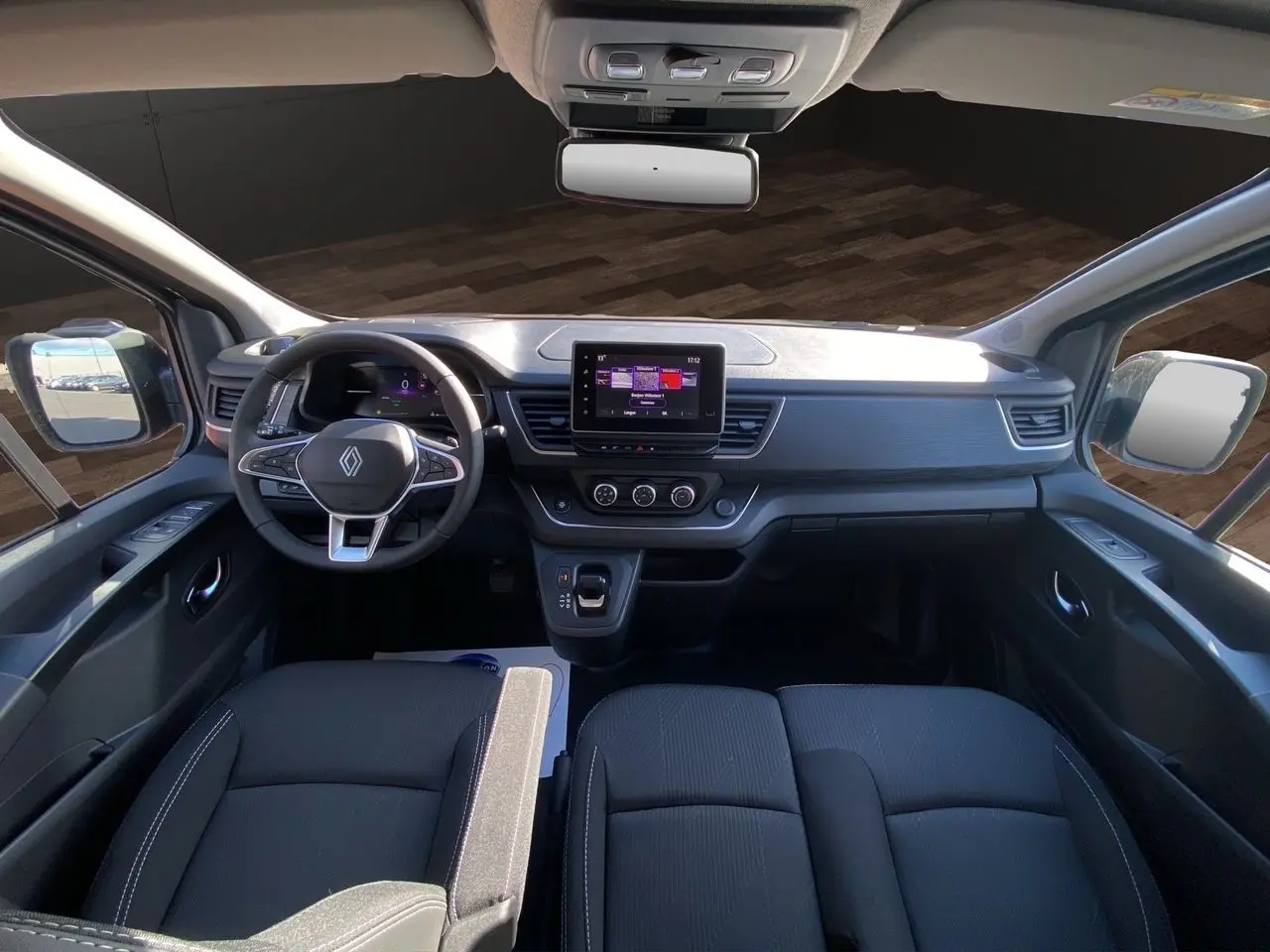 Intérieur noir du Renault Trafic Combi 2025 vu de face, tableau de bord moderne avec écran tactile central.