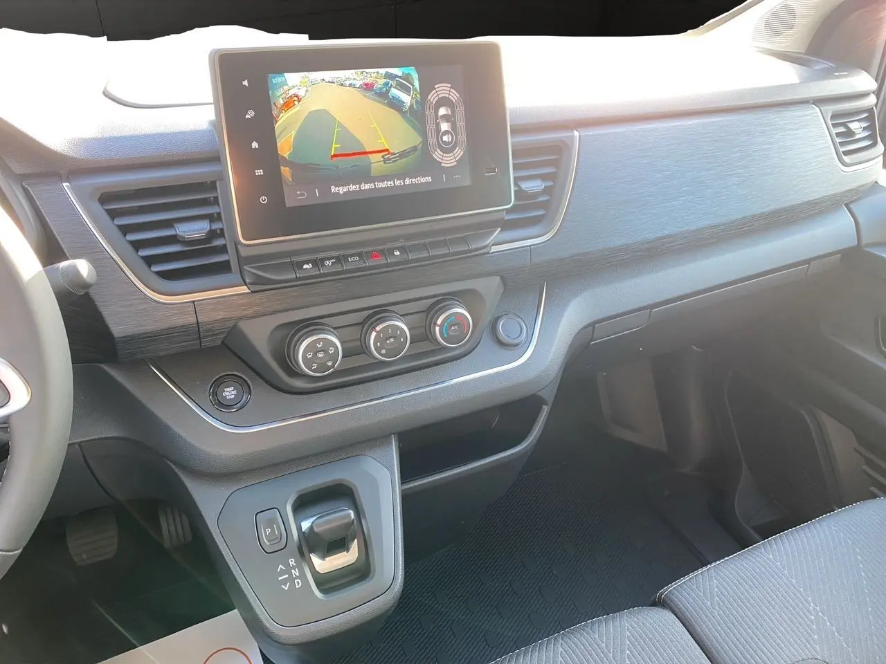 Intérieur avant du Renault Trafic Combi noir 2025, tableau de bord avec écran tactile et levier de boîte automatique.