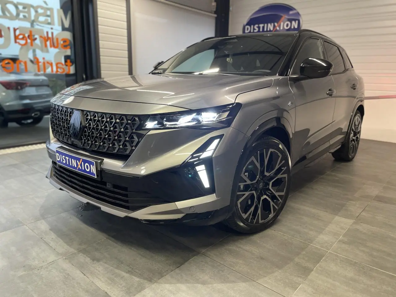 Renault Austral 2025 gris schiste métallisé avec toit noir étoilé, vue 3/4 avant droit mettant en valeur la calandre et les phares LED.